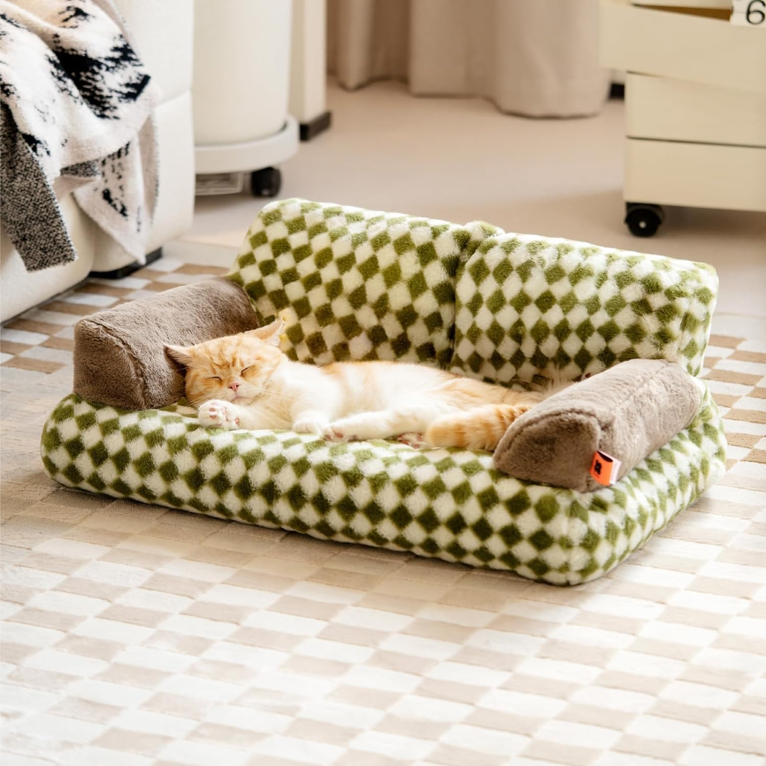 Cat lying on a green and white checkered pet bed in a room.