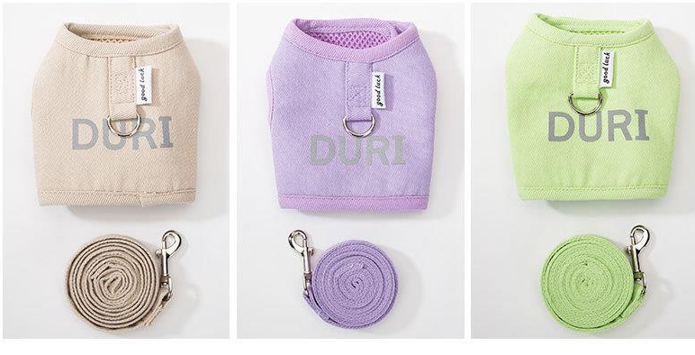 Three cat harnesses in beige, purple, and green with matching leashes on a white background.