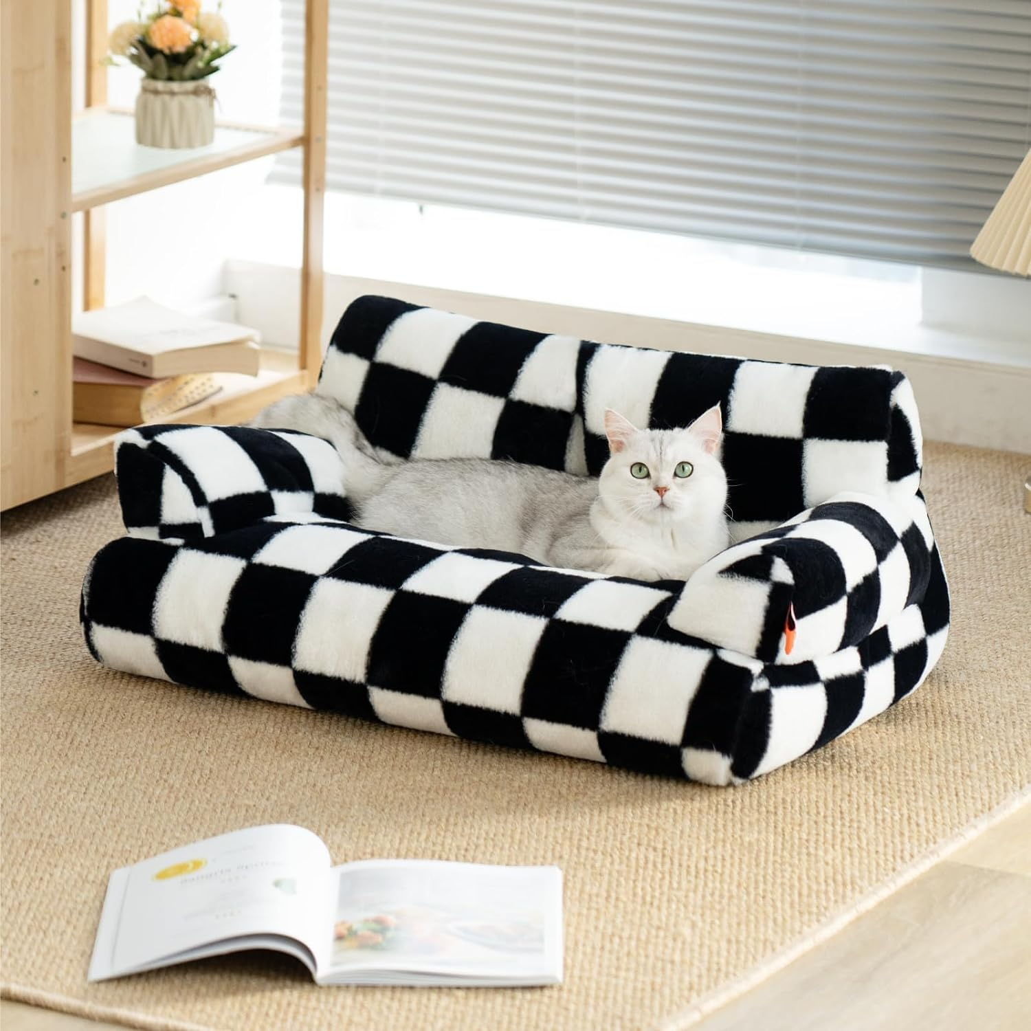 Black and white checkered pet bed with a cat inside, on a carpeted floor.