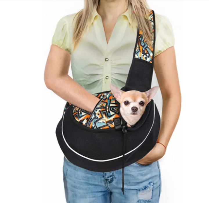 Person holding a black pet sling with a small dog peeking out, on a white background