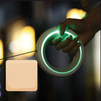 Hand holding a glowing green circular object with a blurred background