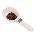 White pet food scoop with brown dog food and digital display on a white background