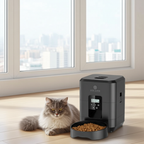 Cat sitting next to a VULUS pet feeder with food on a wooden floor.